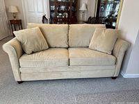 Full front view of the gold microfiber sleeper sofa with four back cushions and two pillows arranged.