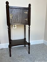 Full view of vintage dark stained wood smoker's stand with cabinet door closed.