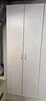 Closed white melamine storage cabinet with 2 doors and plain white handles.