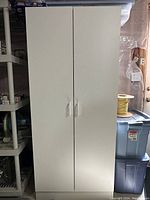 Closed view of the white 2-door storage cabinet showing the front with handles.