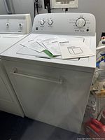 Front view of white top load washer next to matching dryer