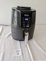 Front view of black Ninja air fryer with digital control panel and timer display. Basket handle visible.