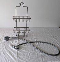 Waterpik handheld shower head with hose and mounting components laid out, next to the metal shower caddy.