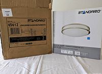 Two STANDARD brand LED ceiling light fixture boxes shown side-by-side with packaging labels visible, indicating brand, type, and specifications.