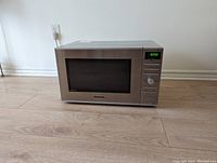 Panasonic microwave oven closed, showing stainless steel body and digital display panel.