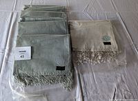 5 handmade scarves (4 blue, 1 white) laid out showing fringe detail and labels, unopened.