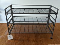 Photo of the assembled shoe rack showing three metal mesh shelves and sturdy frame.