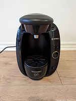 Front view of the Bosch Tassimo coffee maker showing the dispensing area and control panel.