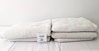 Five white cotton towels folded in two neat stacks on a flat surface.
