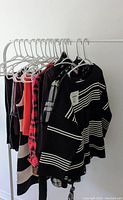 Photo showing multiple women's clothing items on hangers including sweaters, tops, and a plaid shirt