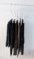 Six pairs of women's pants hanging on hangers showing different colors and styles including black and patterned.
