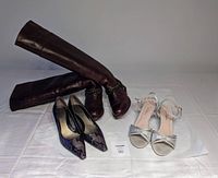 All three pairs of women's shoes shown on a white surface: Sendra tall brown leather boots, Bandolino purple snakeskin heels, and silver glitter De Blossom wedding heels