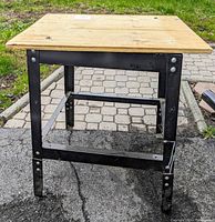 Side view of the work bench showing the metal frame and wooden top