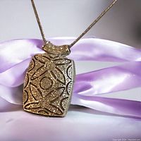 Close-up of rectangular silver marcasite pendant hanging with chain, showing pattern and stone setting.