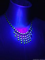 Necklace displayed under UV light to show uranium glass stones fluorescence.