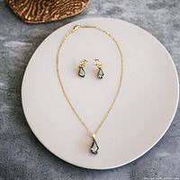 Full view of necklace and earrings set displayed on a round white plate.