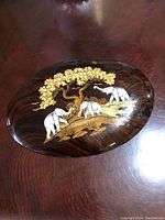 Full view of an oval wooden plaque featuring three white elephants under a tree with inlaid wood carving details.