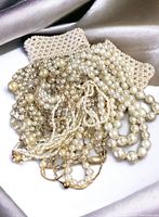 Photo showing all vintage costume pearl necklaces and bracelets piled together on a satin background