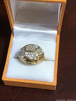Gold plated dome shaped dinner ring with clustered clear stones set in sections on top, displayed in an orange textured box lined with white satin and velvet.