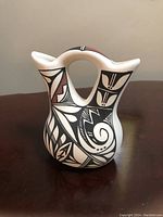 Front view of the vase showing the detailed black and red Native American design on white ceramic.