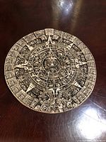 Top view showing entire round Aztec Sunstone Calendar plaque on dark surface.