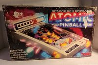 Box of Atomic Pinball arcade game showing flashing lights and spring balls feature