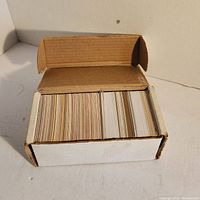 Box filled with a thick stack of hockey cards shown from above inside a brown cardboard box.