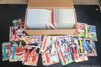 Box filled with large quantity of Pro Set sports cards spread on a black surface with several cards displayed in front showing mostly soccer players.