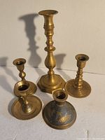 Five candle holders arranged showing front view to see varied heights and bases for each.