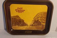 Photo of Coca-Cola 60th Anniversary commemorative tray showing a sepia-tone historic street scene in Vancouver with brown edges and Coca-Cola branding.
