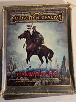 Box cover for Forgotten Realms Campaign Set showing a warrior on horseback with a ruined city background, edges of the box worn and frayed.