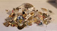 Wide view showing a scattered grouping of many different pins, some individually bagged with tags and price stickers.