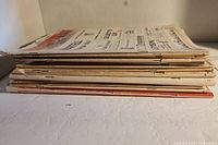 Side view of stack of 11 vintage magazines showing thickness and aged condition.