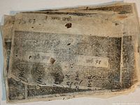 Stack of thin paper documentary stamps with black intricate border designs and '9 Paisa' denomination in Indian script, showing wear and some handwritten markings.