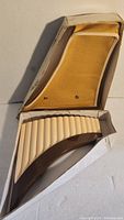 Curved plastic panflute in original box with yellow fabric lining and worn cardboard box.