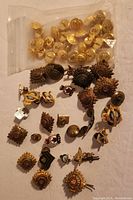 Overview photo of mixed Shriner and military pins and buttons scattered with a bag of small gold-tone buttons.