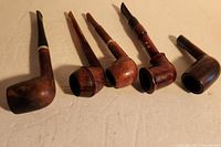 Photo displaying all five wooden tobacco pipes from a side angle showcasing varying bowl shapes and stem lengths.
