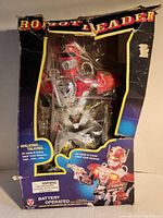 Front view of battery operated robot toy 'Zadak' in original heavily damaged packaging showing robot inside and packaging details.