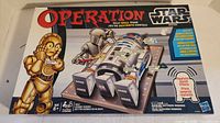 Box front of Star Wars Operation game showing the title, main characters C-3PO and R2-D2, and game illustration.