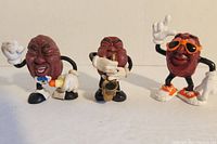 Three Musical Raisins cartoon grape character figurines: trumpet player, saxophone player, and dancer with sunglasses.