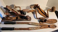 Full lot of vintage hand tools on a white surface showing wood and metal tools aged with rust and wear.
