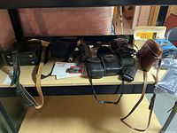 Overview photo showing multiple vintage camera bags and cases, some with straps and different sizes and materials.