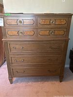 Front view of the Gibbard wood dresser showing decorative upper drawers with round metal pulls and plain lower drawers with horizontal metal handles.