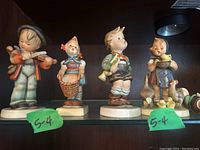 Front view of four intact Hummel figurines depicting children with violin, basket, and geese.