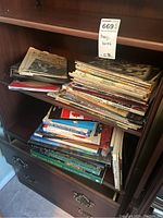 Photo showing stacks of newspapers, magazines and books on wooden shelves.