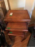 Top-down view showcasing three stacked wooden nesting tables with warm brown finish and rounded legs.