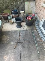 Overall view of planters, watering cans, plant cages, and metal shepherd's hooks on backyard patio.