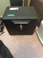 Black SentrySafe 1170 security safe closed, showing locking key inserted and compact design.