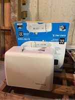 Closed white hard plastic cover case for the sewing machine with Euro-Pro X logo.