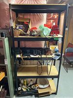 Full view of metal frame shelf with various items on shelves, including bags, boxes, small electronics, film rolls, and scale, to show size and structure.
